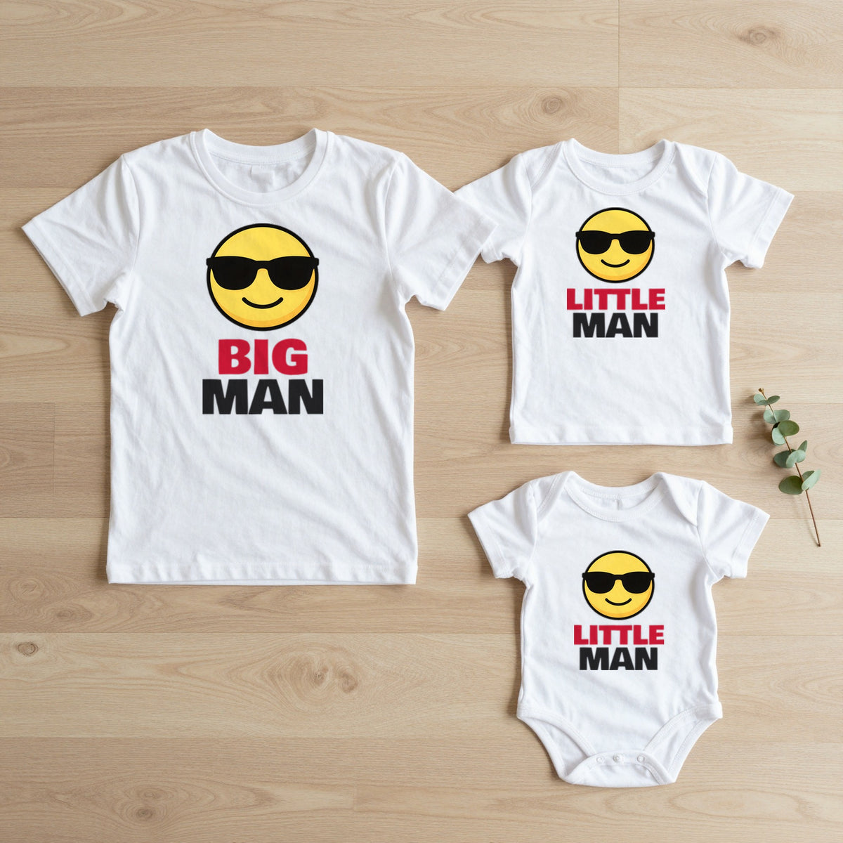 Big Man & Little Man matching set flat lay on oak floor: grown-up tee, kids tee and baby grow