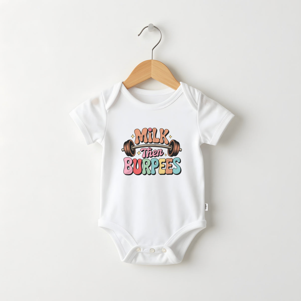 Milk Then Burpees white baby grow on a hanger