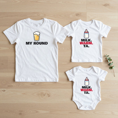 My Round & Milk Warm Ta matching set flat lay on oak floor: grown-up tee, kids tee and baby grow