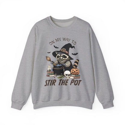 light pink sweatshirt with raccoon witch stirring cauldron halloween design