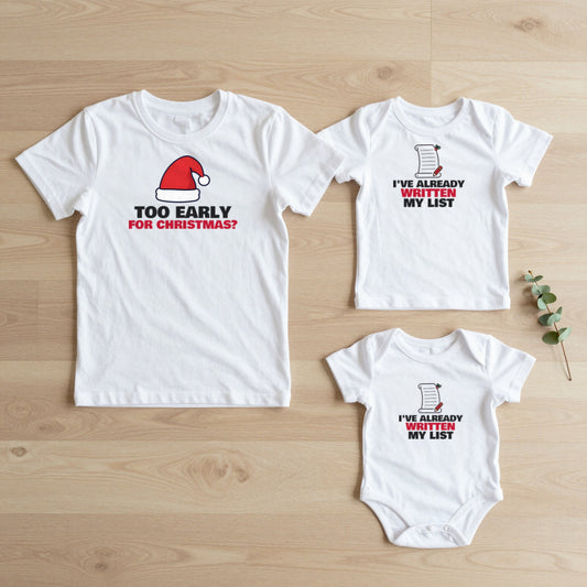 Too Early For Christmas & Already Written My List matching set flat lay on oak floor: grown-up tee, kids tee and baby grow